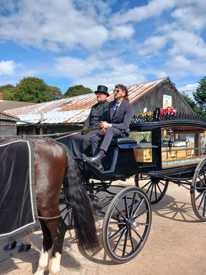 Horse-drawn hearse with two mourners.