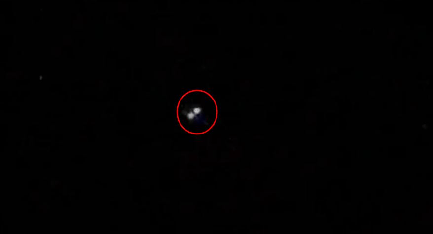 A pair of bright white lights in a dark sky are circled in red.