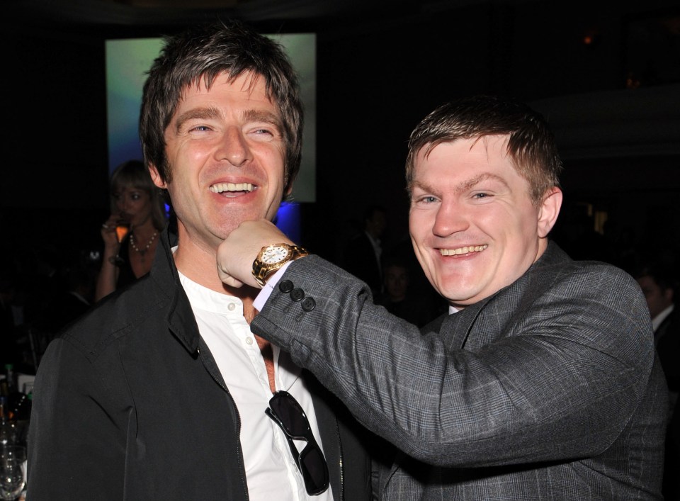 Noel Gallagher smiling as Ricky Hatton playfully punches him under the chin.
