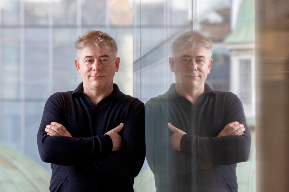 Greg Jackson, chief executive officer of Octopus Energy Ltd., stands with his arms crossed next to his reflection in a window.