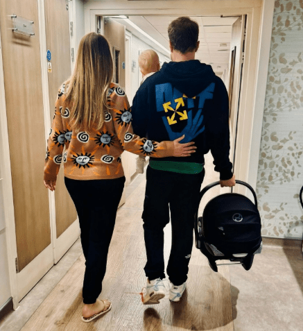 Couple walking with baby and car seat.