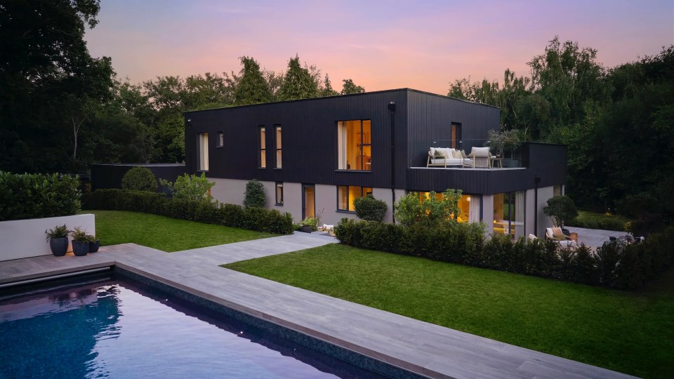 Modern black house with pool at dusk.