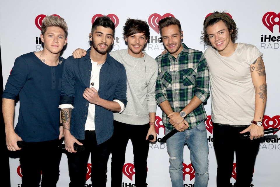 The band One Direction (Niall Horan, Zayn Malik, Louis Tomlinson, Liam Payne, and Harry Styles) standing in front of an iHeartRadio backdrop.