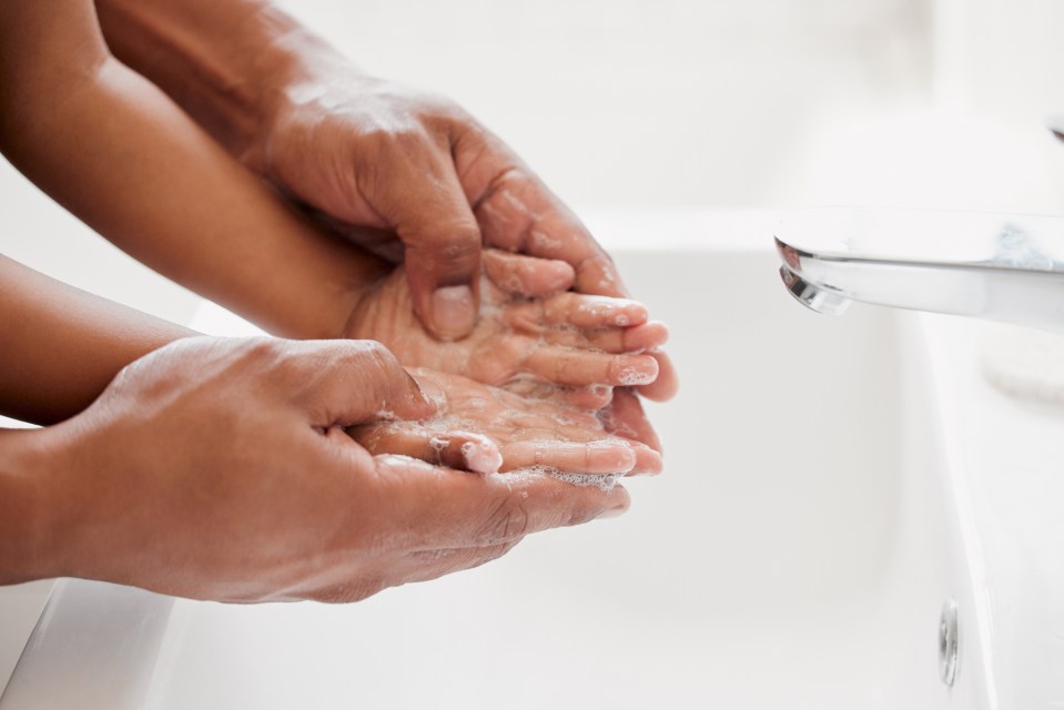 Adult's hands washing a child's hands.
