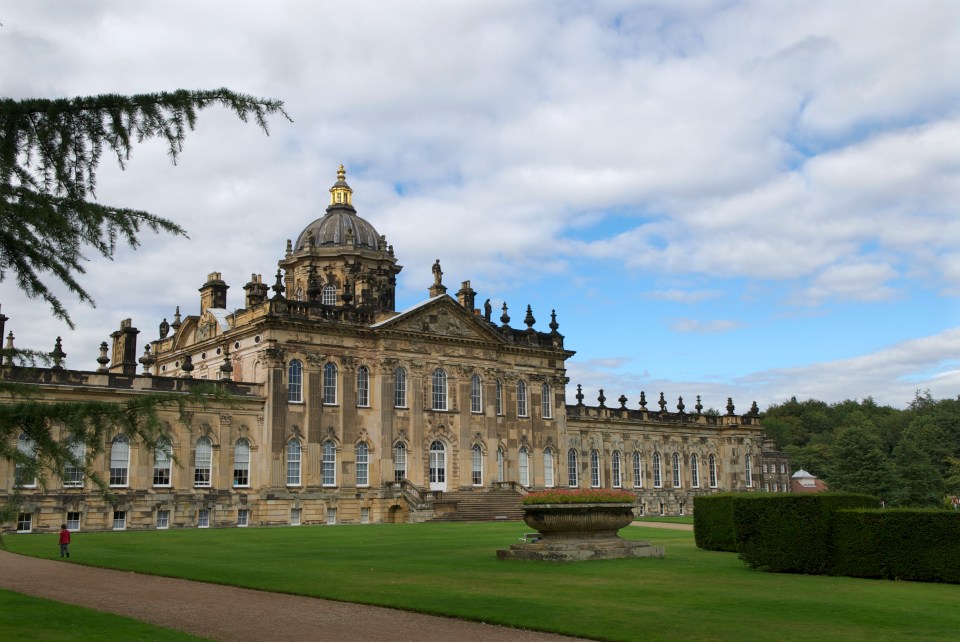 Castle Howard, a large stately home, on a sunny day with green grass and trees.