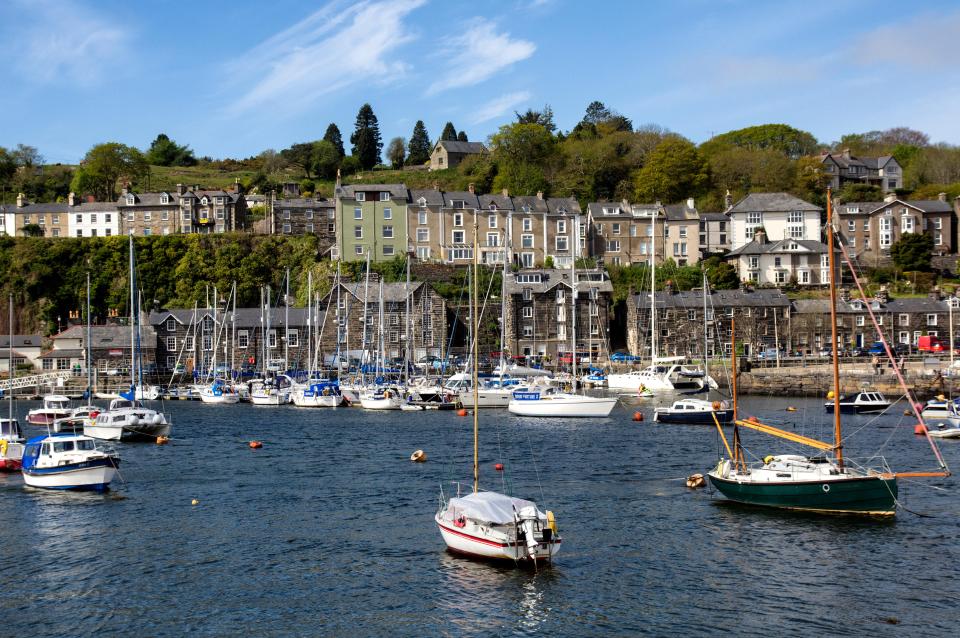 Porthmadog Harbour in Gwynedd, North Wales, with many boats and houses along the hillside.