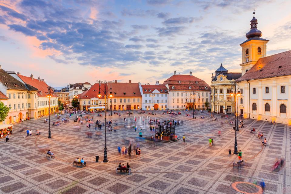 Sibiu's Large Square at sunset, featuring the City Hall and Brukenthal Palace.