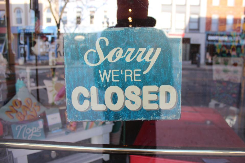 A teal sign in a shop window that reads "Sorry We're Closed".