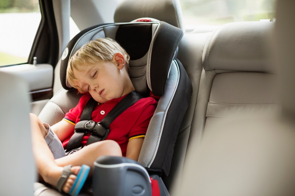 Young boy sleeping in a car seat.