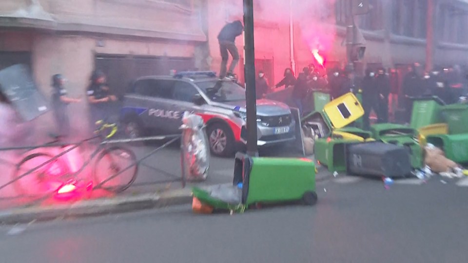 Protester on police car during Paris protest.