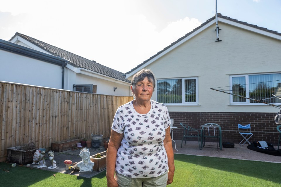 A pensioner stands in her garden.