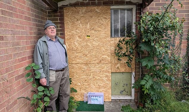 Nicholas Michaels, 69, pictured outside his front door which is still broken a month after police battered it down