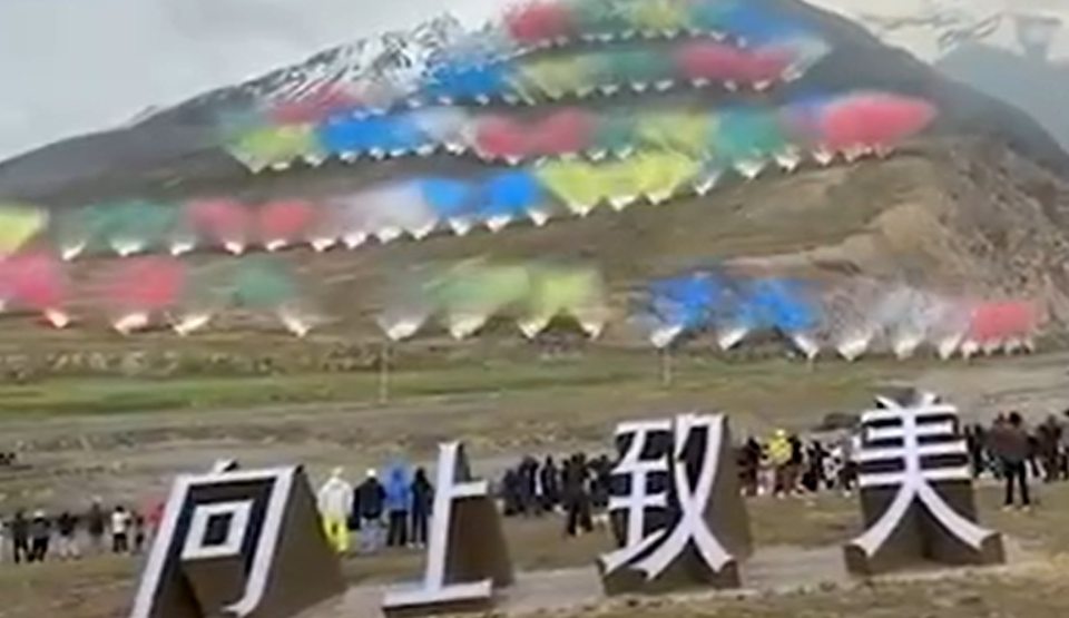 Fireworks display with multiple colorful plumes of smoke on a mountainside, above large white Chinese characters.