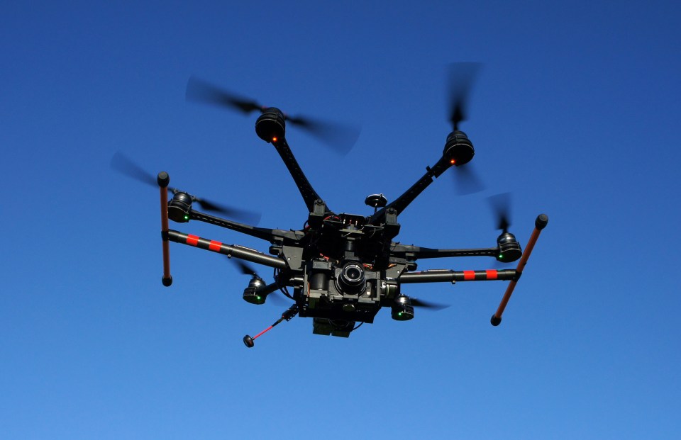 Large drone with camera in flight.