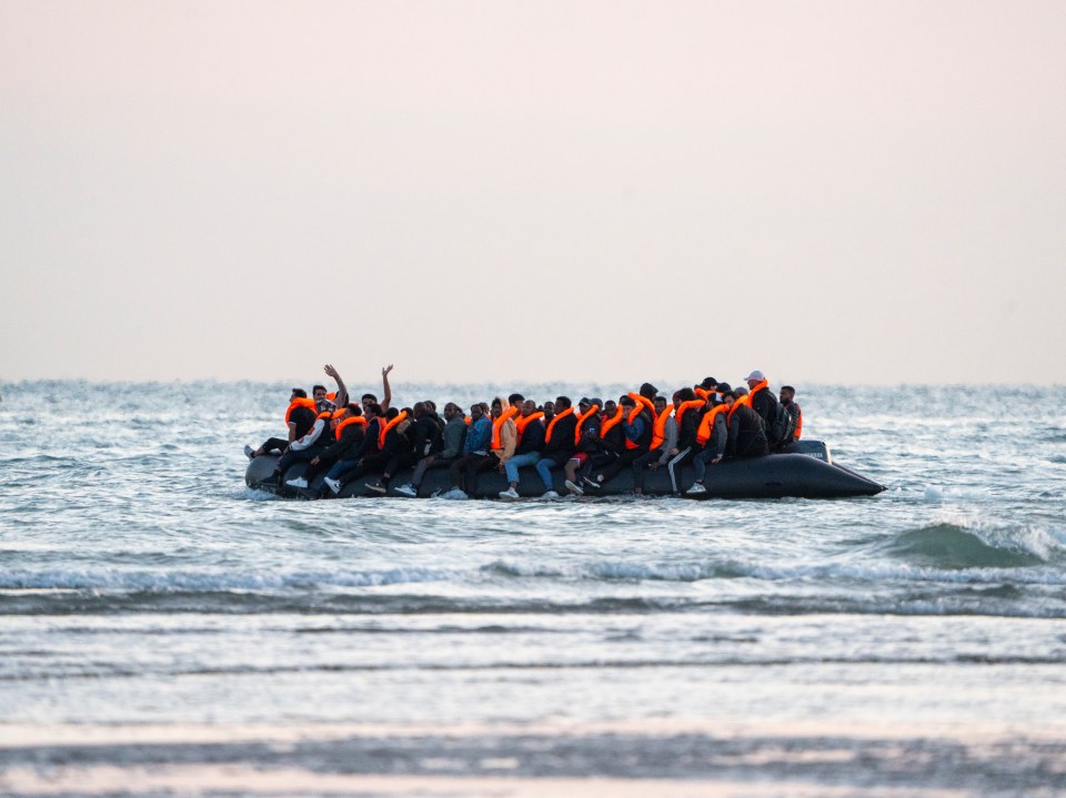 Migrants wearing orange life jackets on a dinghy leaving France.
