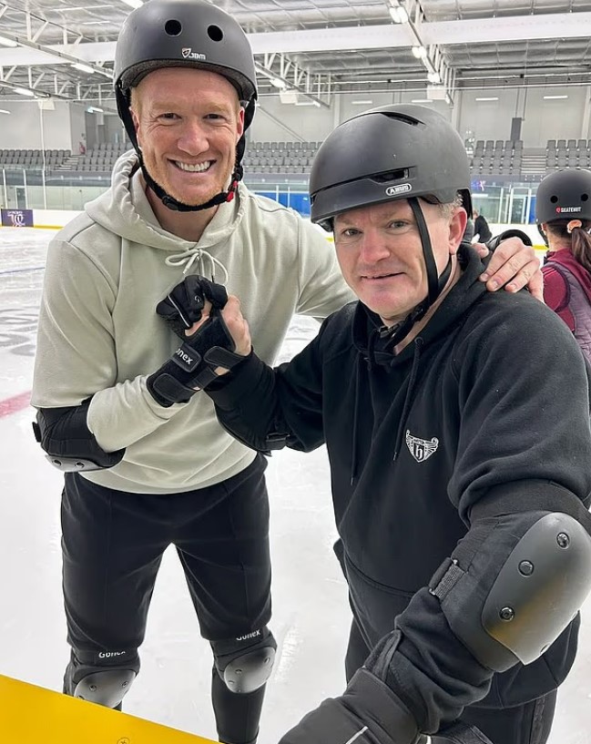 Two men ice skating in protective gear.