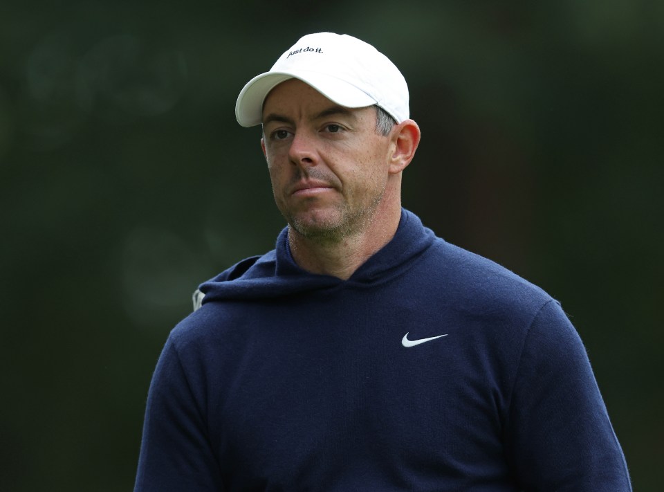 Rory McIlroy wearing a white "Just Do It" cap and a navy blue hoodie with a white Nike swoosh.