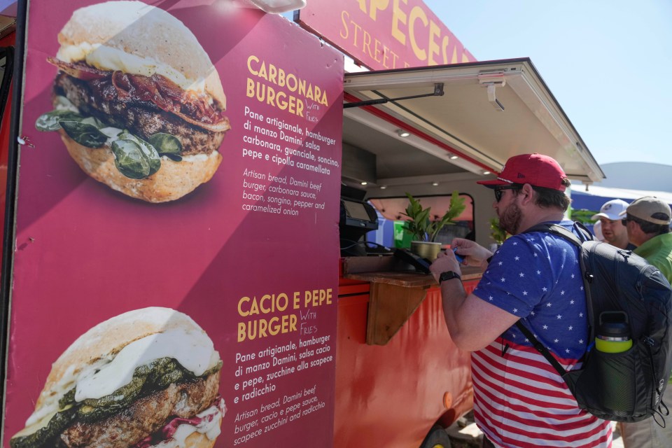 Spectator at the APECESARE food truck looking at a menu advertising Carbonara and Cacio e Pepe burgers with descriptions in Italian and English.