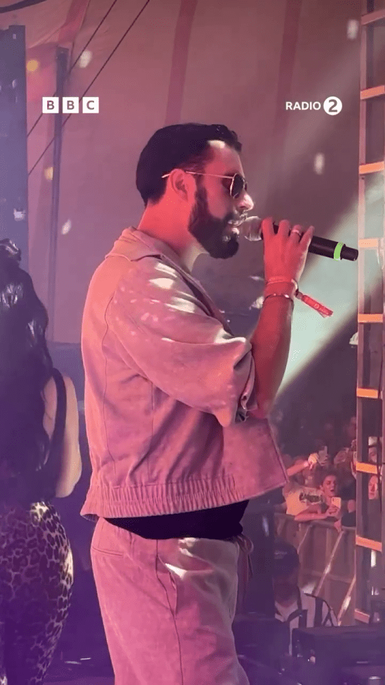 Rylan Clark singing into a microphone on stage.