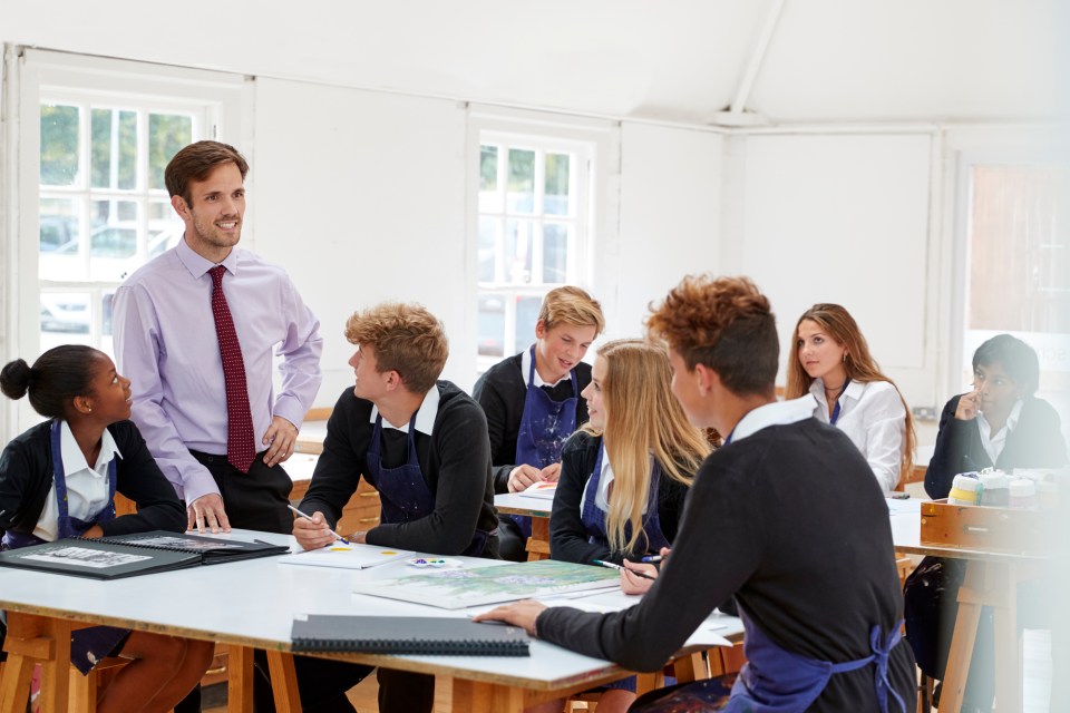 Teacher instructing teenage students in an art class.