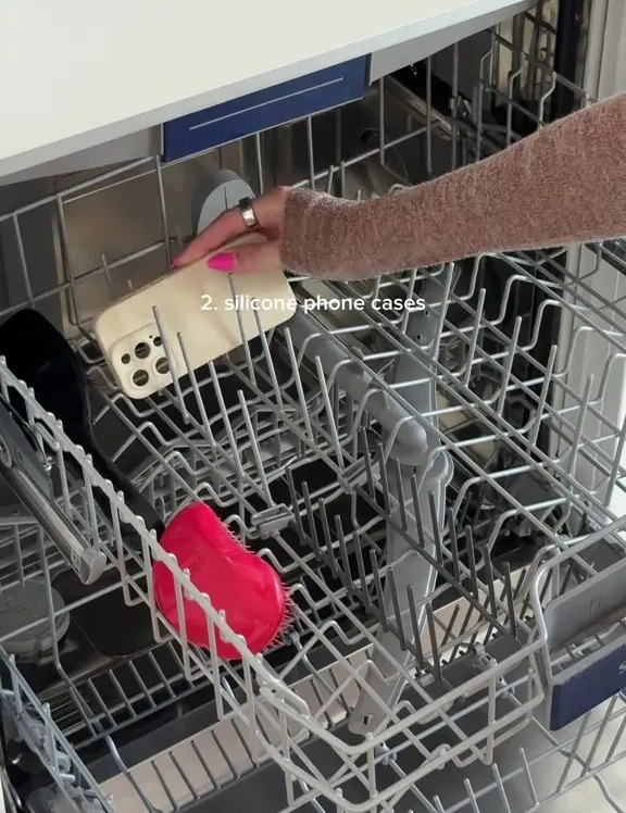 A person loading silicone phone cases into a dishwasher.