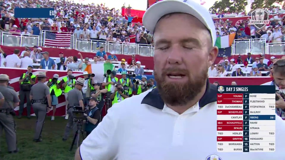 Shane Lowry crying with a golf score board and a crowd in the background at the Ryder Cup.