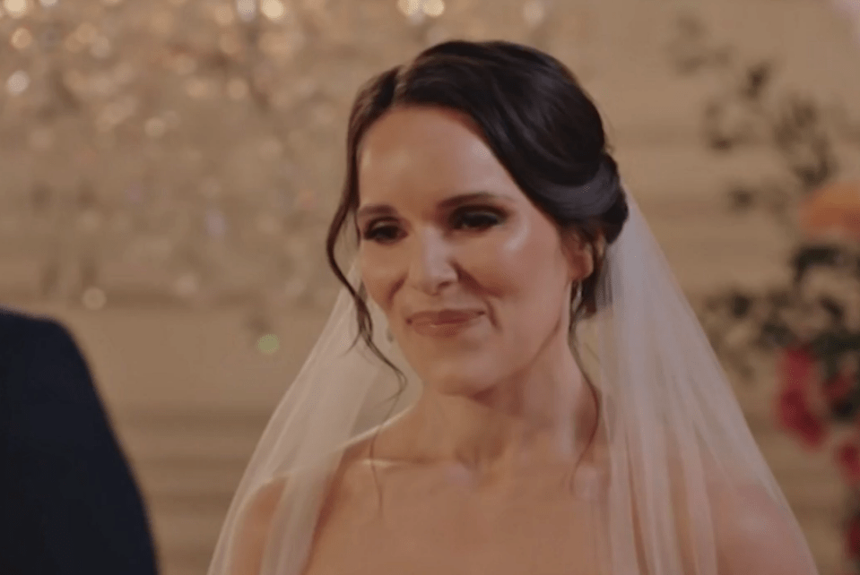 A woman in a wedding dress looking at the groom.