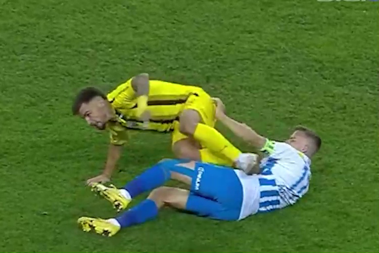 Nicusor Bancu on the ground while a Universitatea player in yellow is on top of him.
