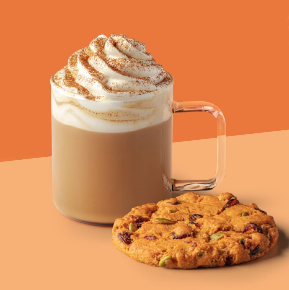 A Starbucks Pumpkin Spice Latte with whipped cream and a cookie with cranberries and pumpkin seeds.