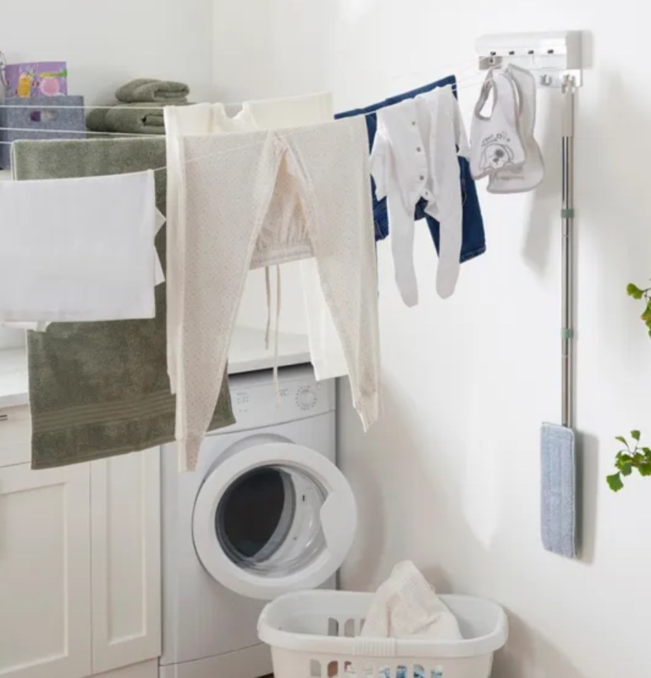 Laundry drying on a wall-mounted clothesline next to a washing machine.