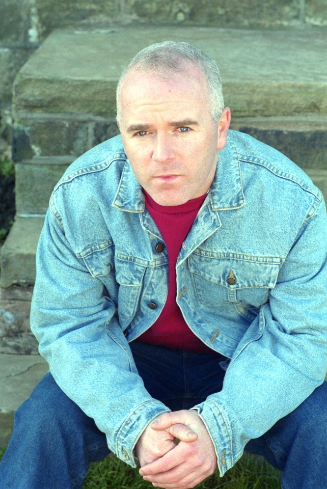 a man in a denim jacket sits on a set of steps