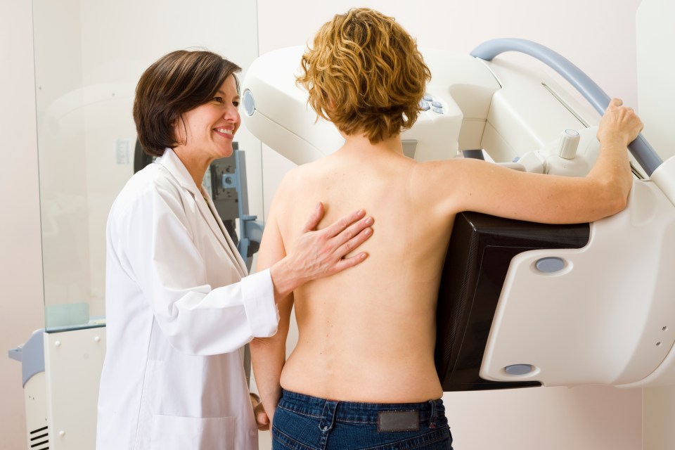 Medical technician helping a woman prepare for a mammogram.