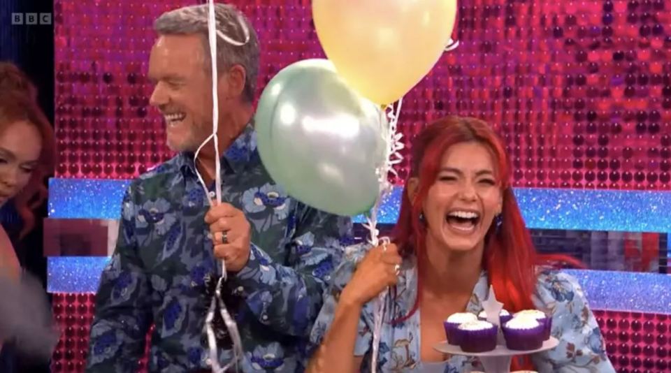 Dianne Buswell and Stefan Dennis holding balloons and laughing, with cupcakes on a tray.