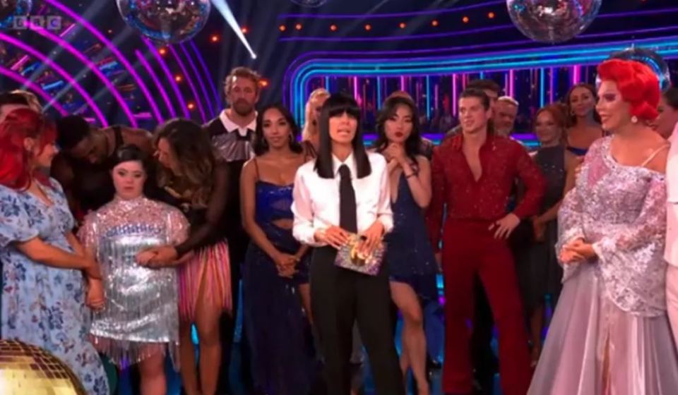 Ellie Goldstein appears upset while being supported by professional dancers on a stage.