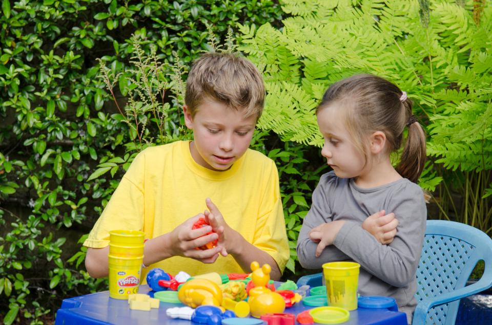 Brother and sister playing with Play-Doh outside.