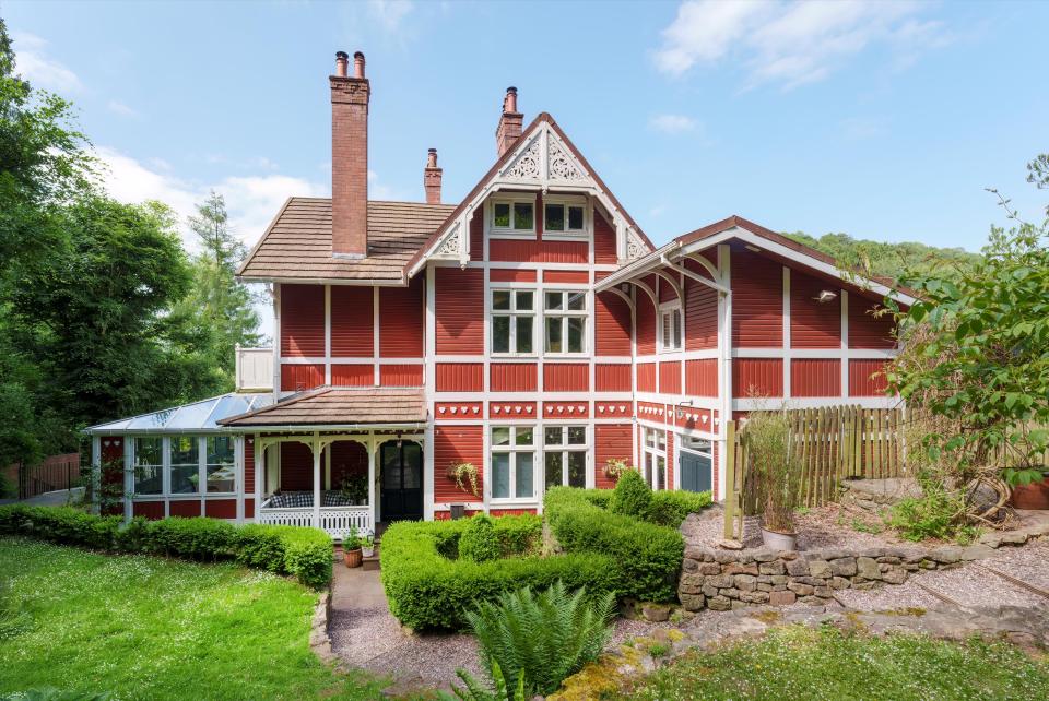 Norwegian former fishing lodge in red and white surrounded by green foliage.