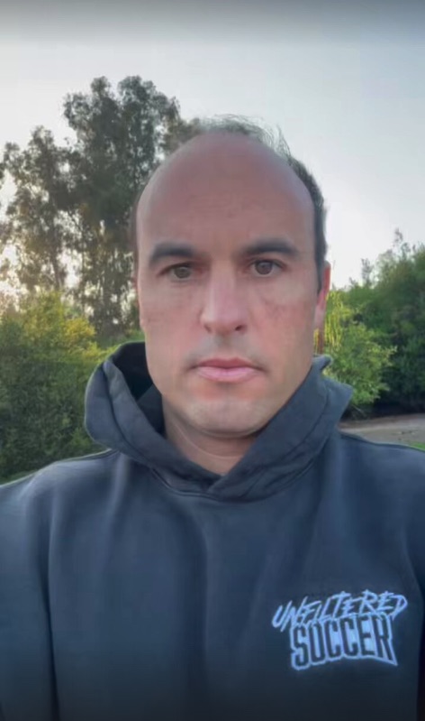 A man in a black "Unfiltered Soccer" hoodie looks at the camera.