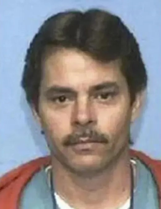 Mugshot of Robert Eugene Brashers, a man with dark hair and a mustache, wearing an orange and blue shirt.