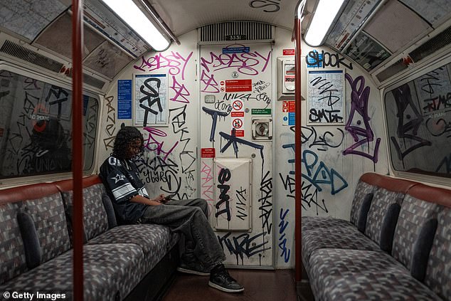 A London Underground passenger sits in a Bakerloo Line carriage covered in graffiti in June