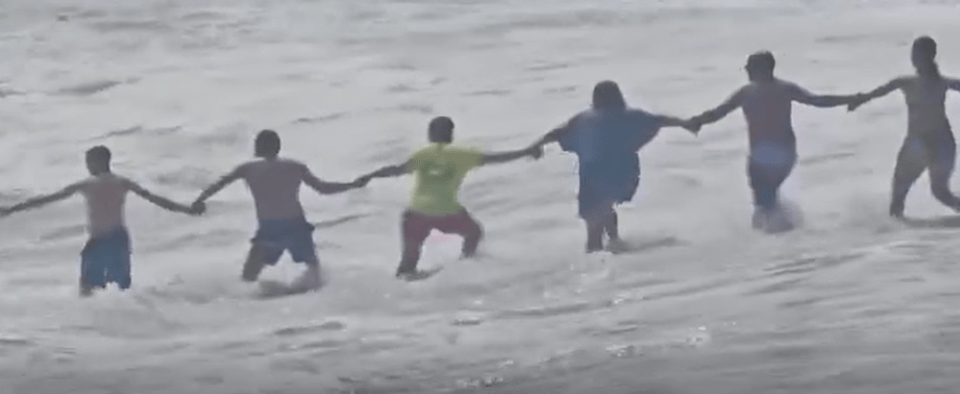 Human chain rescuing a child from strong currents.