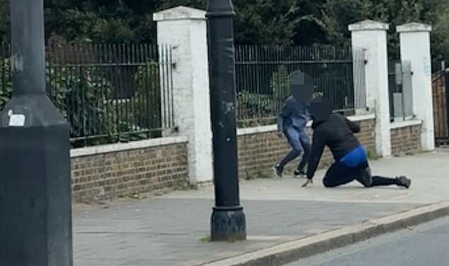 In shocking footage, a youth dressed in navy jogging bottoms and a hoodie plunges towards several teenagers, appearing to strike one within seconds