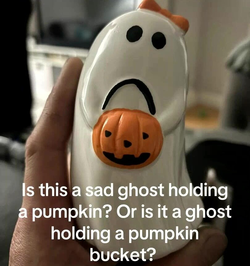 A ceramic ghost decoration that appears to be sad or holding a pumpkin.