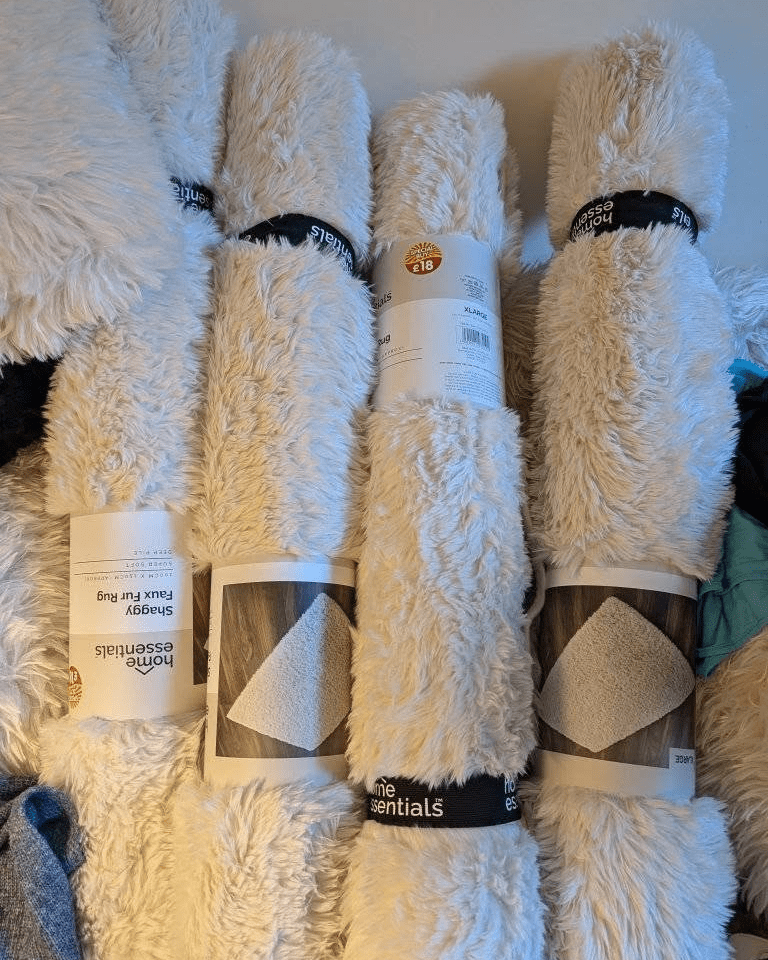 Four rolled-up white shag faux fur rugs.