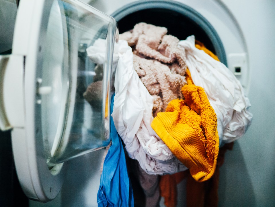 Clothes being loaded into a washing machine.