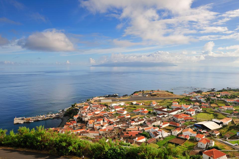 Panoramic view of Vila Nova do Corvo, Azores, with the ocean and another island in the background.