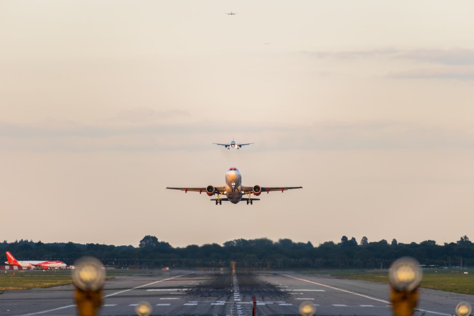 An easyJet Airlines plane takes off from Gatwick Airport, with planes landing in the background.