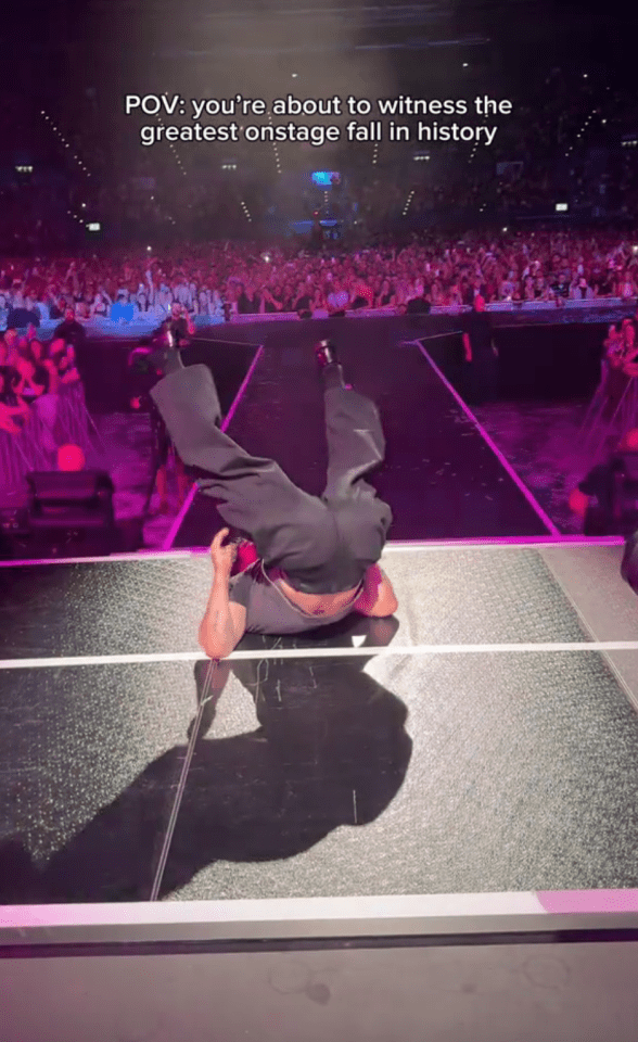 Person falling on stage in front of a large audience.