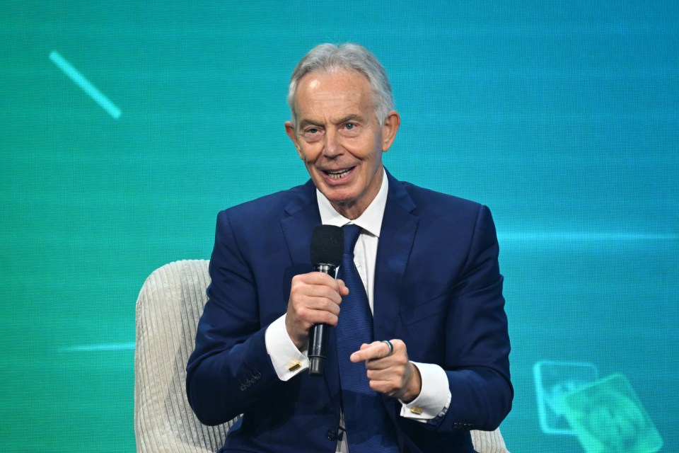 Tony Blair speaking into a microphone while sitting in a chair.