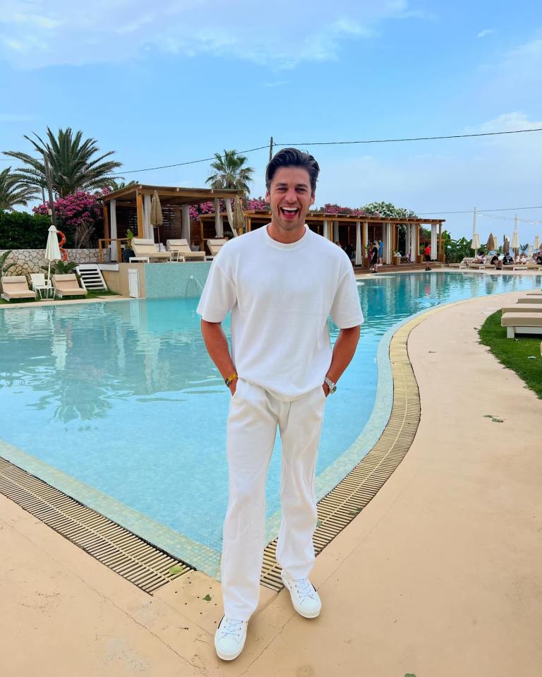 Too Hot To Handle star Harry Johnson standing beside a swimming pool.