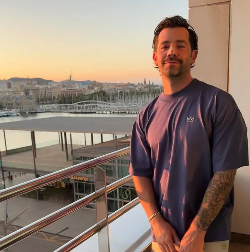 Charlie King on a balcony overlooking a city at sunset.